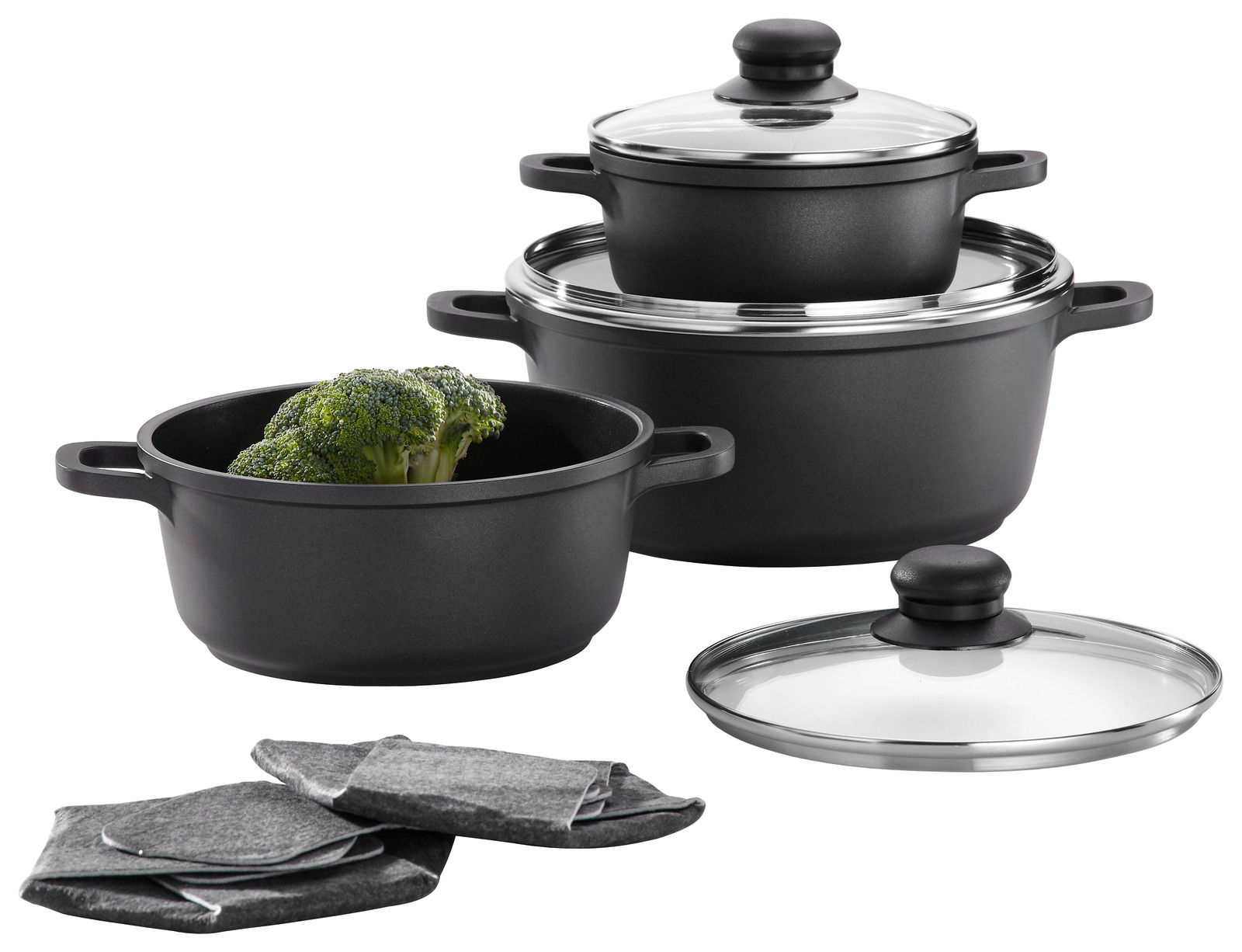 Topf Set 3-teilig, bestehend aus drei schwarzen Töpfen mit Glasdeckeln, in einer leicht seitlichen Perspektive. Ein Topf enthält Brokkoli, daneben liegen graue Topflappen.