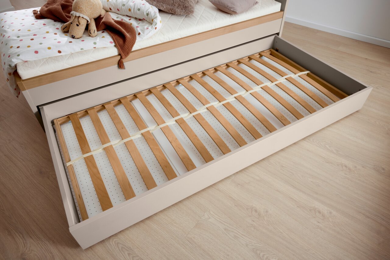 Bettkasten mit Lattenrost, herausgezogen unter einem Bett, von oben fotografiert.
