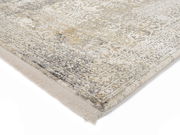 Nahaufnahme eines Designer-Teppichs mit detailliertem Muster in Grau- und Beigetönen, perspektivisch von der Ecke aufgenommen.