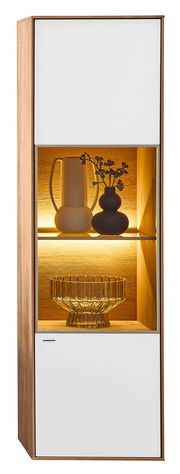 Hängevitrine Valnatura LAGO in Holzoptik mit zwei weißen Türen und beleuchtetem Glasfach, seitliche Perspektive.