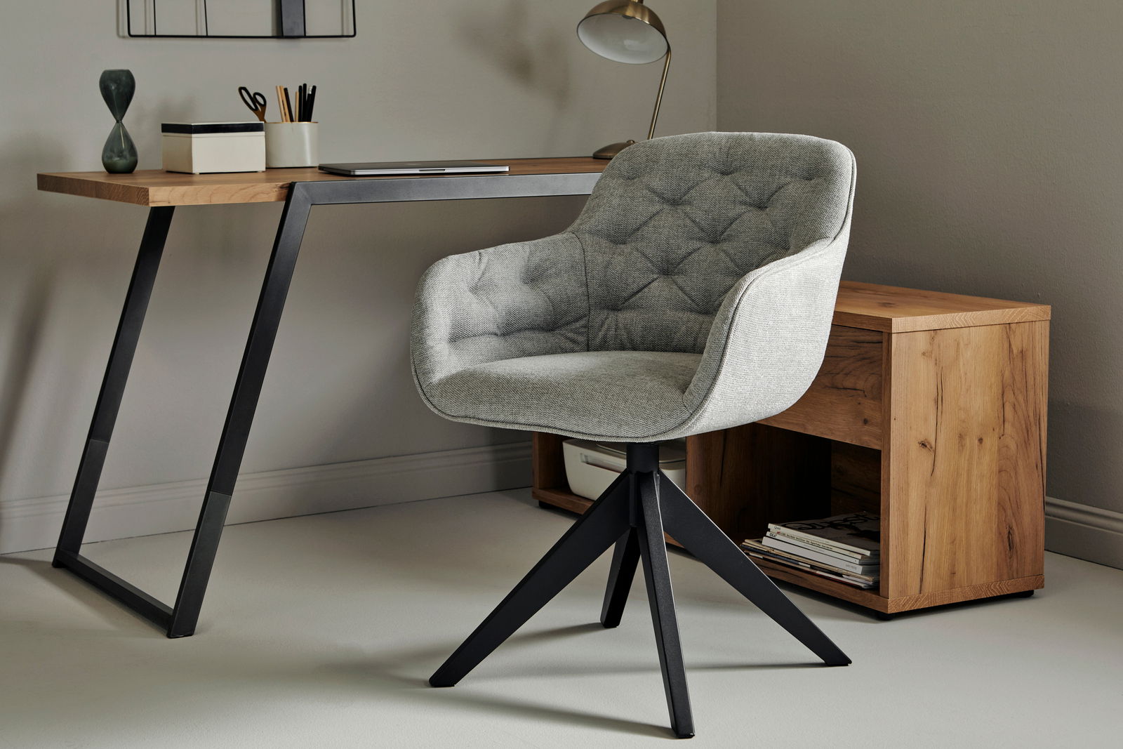 Grauer, gepolsterter Stuhl mit Armlehnen und schwarzem Metallgestell, seitliche Perspektive