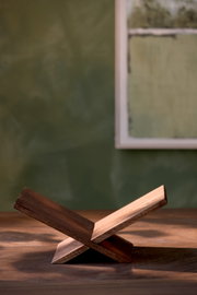 Minimalistischer klappbarer Buchständer aus dunklem Holz in seitlicher Nahansicht auf einem Holztisch