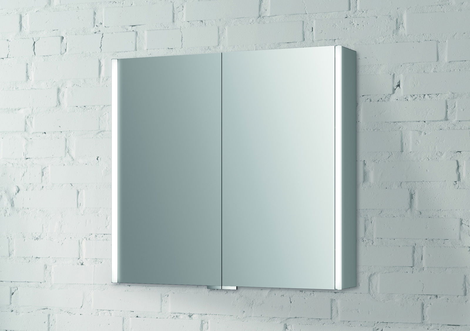 Moderner Spiegelschrank mit zwei Türen, frontal an einer weißen Ziegelwand montiert.