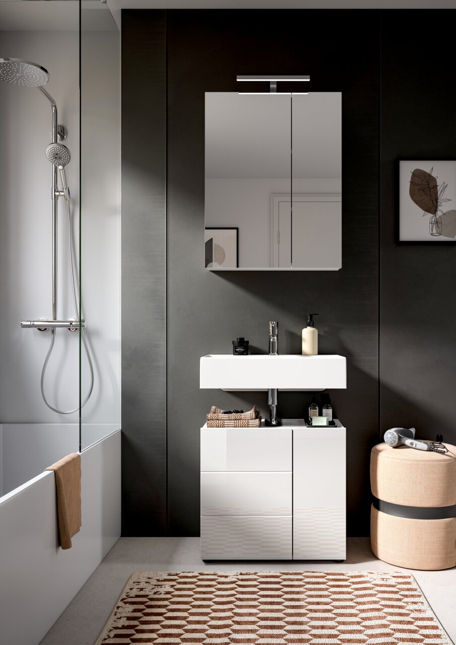 Moderne Badkombination mit weißem Waschbecken und Unterschrank, Spiegel mit Beleuchtung, seitlicher Duschbereich und dekorative Elemente, Frontalansicht.
