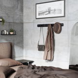 Moderne Wandgarderobe in einem stilvollen Schlafzimmer, frontal betrachtet, mit Hut, Mantel und Tasche behängt.