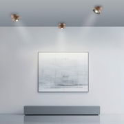 Moderne LED-Deckenleuchte in einem minimalistischen Raum, von unten betrachtet, mit drei Strahlern, die ein Kunstwerk an der Wand beleuchten.