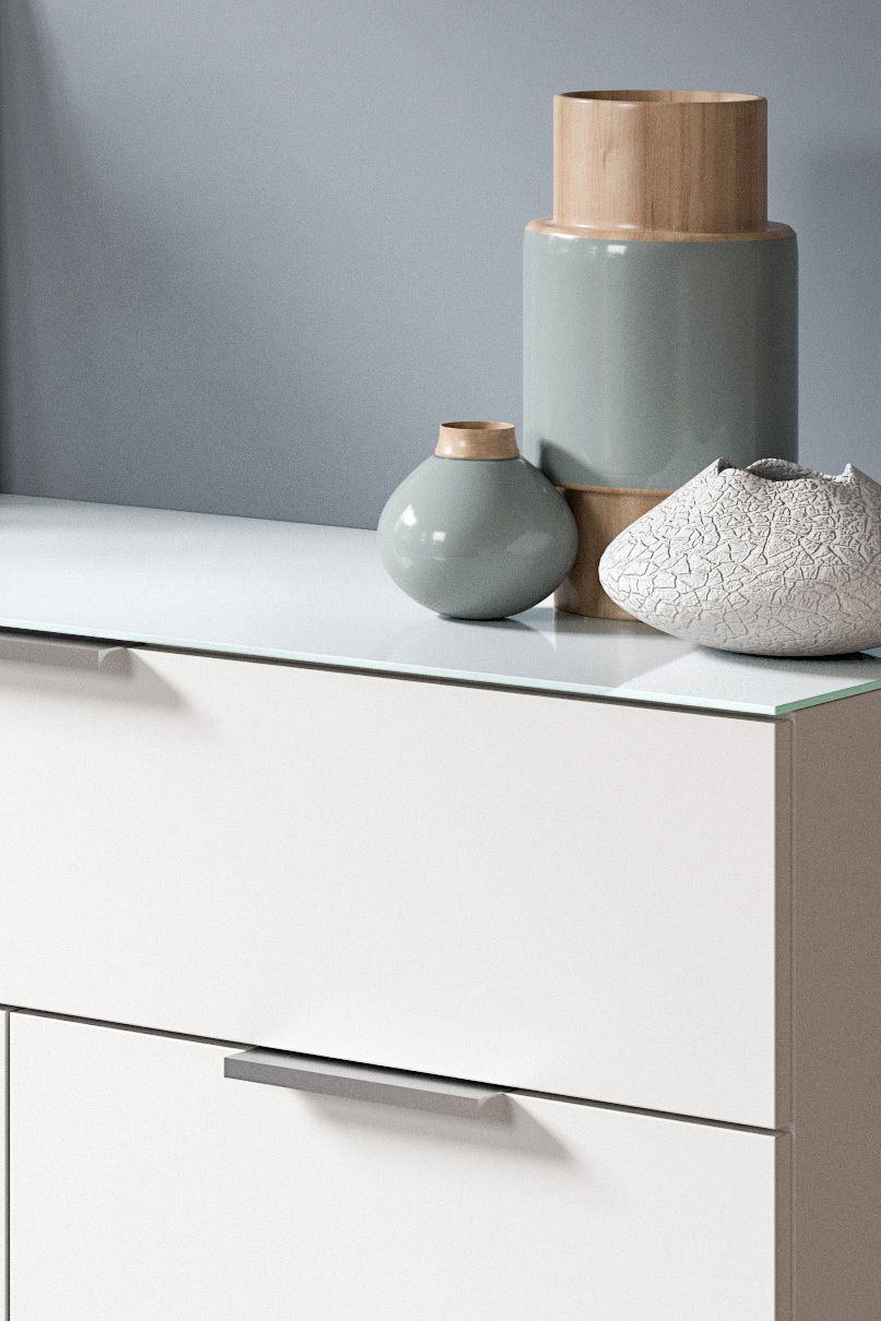 Nahaufnahme einer modernen Kommode mit dekorativen Vasen und einer Schale auf der Oberseite, seitliche Perspektive.