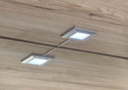 Zwei quadratische LED-Leuchten in einem Holzschrank, von unten betrachtet.