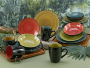 Kombiservice 16-tlg in tropischer Umgebung, bestehend aus bunten Tellern und Tassen, aus der Vorderansicht fotografiert.