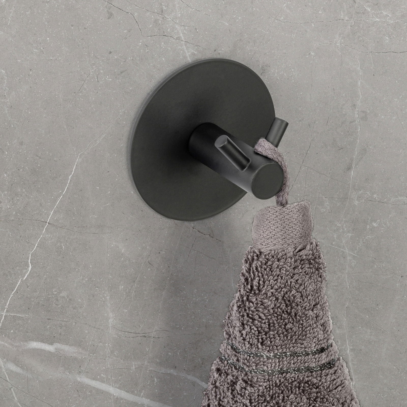 Schöner Wohnen Wandhaken MELETO Schwarzer Wandhaken Duo Meleto an einer grauen Wand, von oben fotografiert, mit einem grauen Handtuch daran hängend.