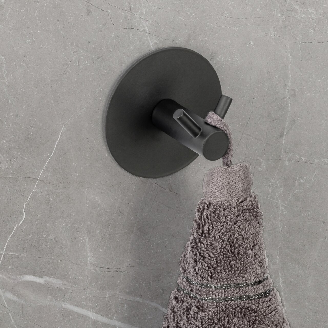 Schöner Wohnen Wandhaken MELETO Schwarzer Wandhaken Duo Meleto an einer grauen Wand, von oben fotografiert, mit einem grauen Handtuch daran hängend.
