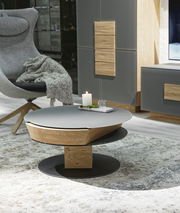 Moderner Couchtisch mit runder, grauer Tischplatte und Holzdetails, seitliche Perspektive