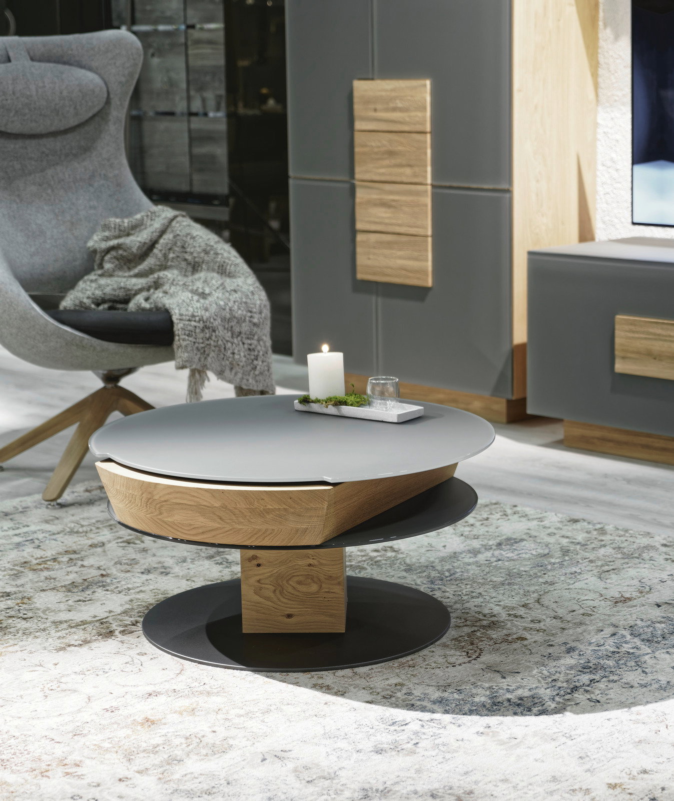 Moderner Couchtisch mit runder, grauer Tischplatte und Holzdetails, seitliche Perspektive