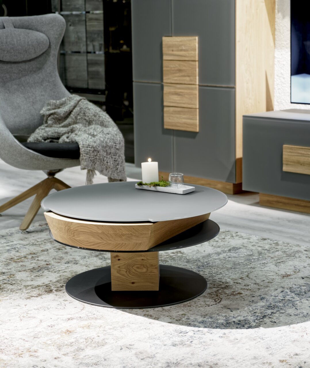Moderner Couchtisch mit runder, grauer Tischplatte und Holzdetails, seitliche Perspektive