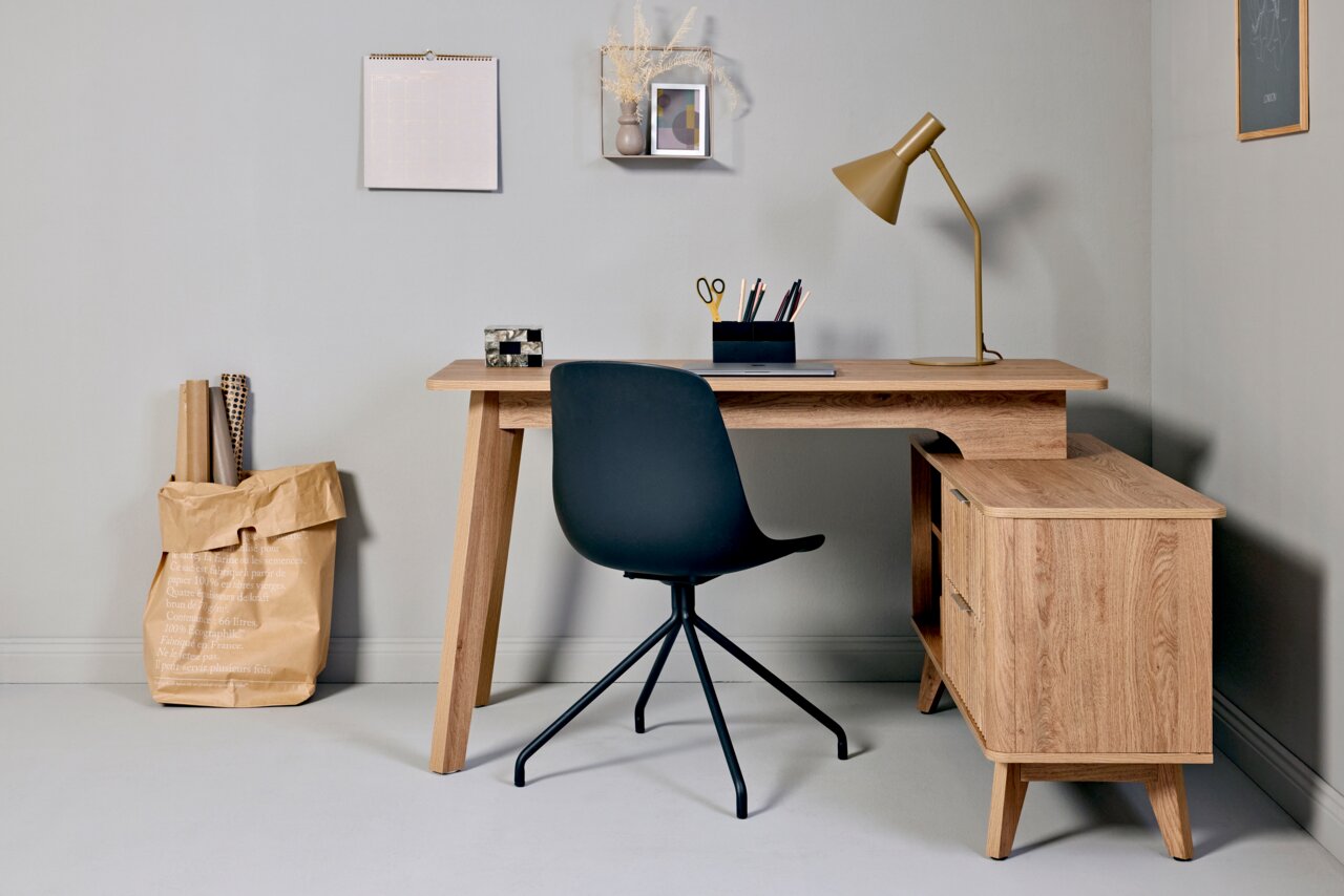 Moderner Eck-Schreibtisch aus Holz mit Stauraum, schwarzem Stuhl und Schreibtischlampe, aus der Perspektive von vorne.