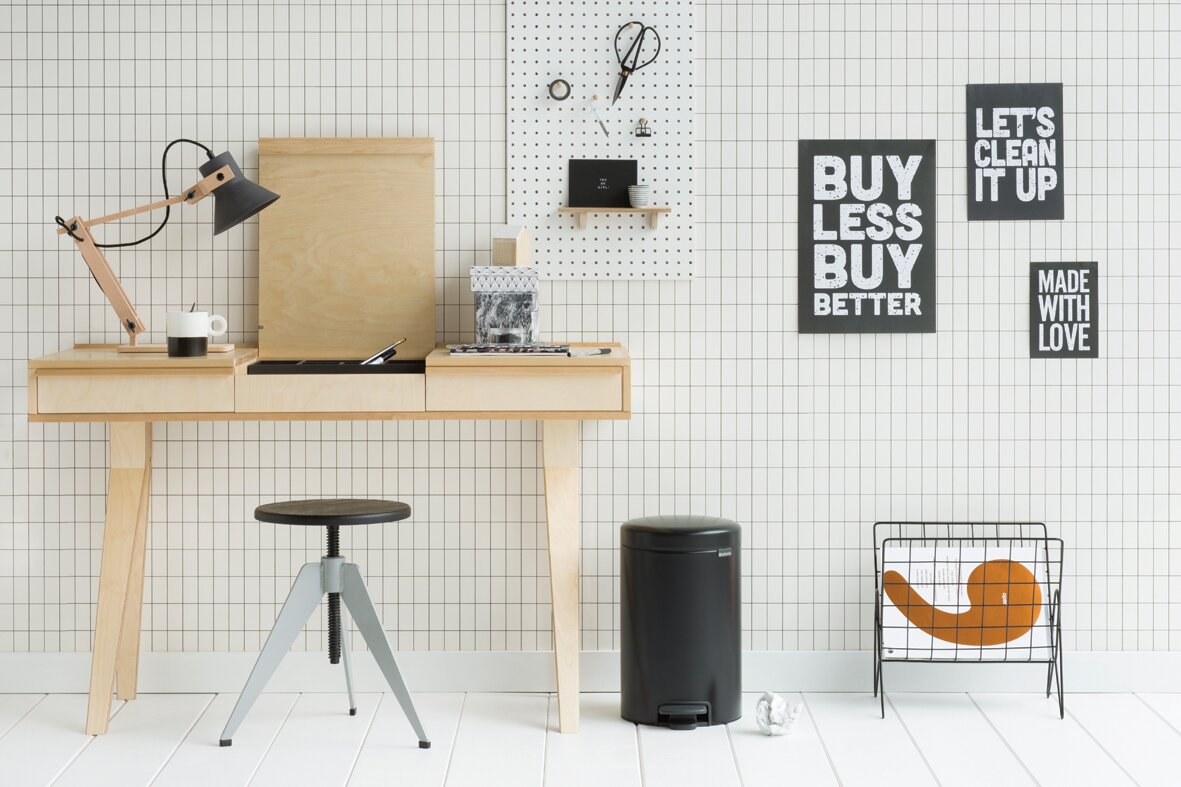 Brabantia Treteimer NEWLCON Schwarzer Treteimer in einem modernen, minimalistischen Raum mit hellem Holztisch und dekorativen Wandbildern, seitliche Perspektive.