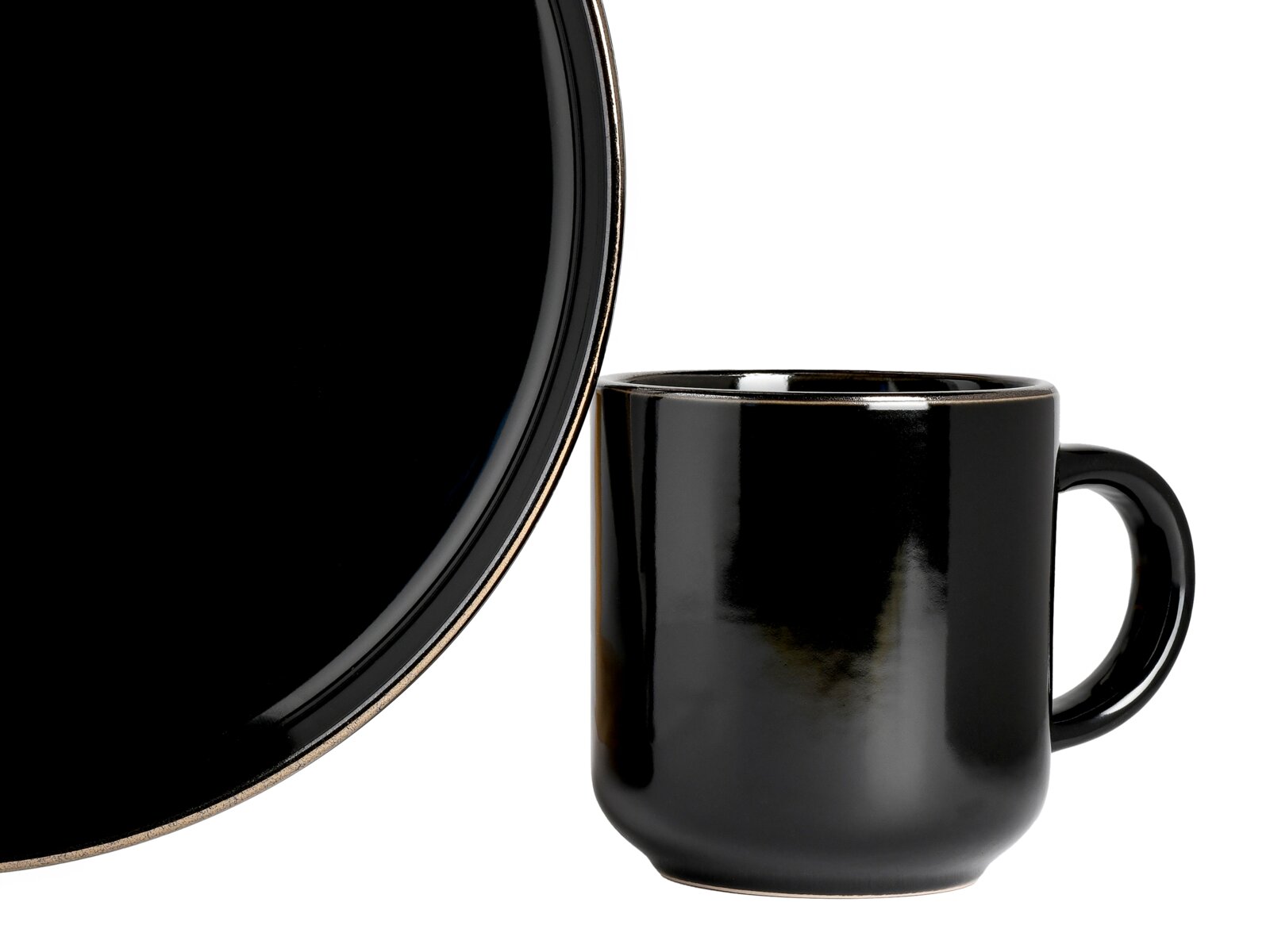 Schwarze, glänzende Keramiktasse mit Henkel neben einem passenden schwarzen Teller mit beigem Rand, seitliche Ansicht vor weißem Hintergrund