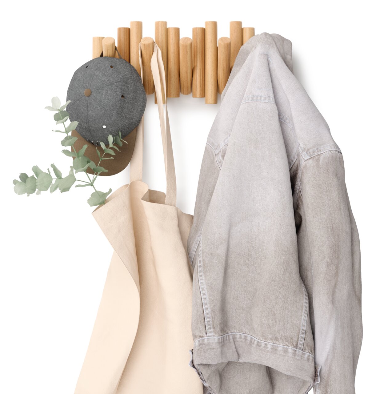 Wandgarderobe aus Holz mit Haken, an denen eine graue Mütze, eine beige Tasche und eine graue Jacke hängen. Frontalansicht.