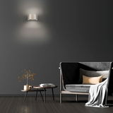 Moderne Wandleuchte PURE Clipse in einem stilvollen Wohnzimmer, frontal an der Wand montiert, mit sanftem Lichtschein.
