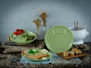Grünes, glänzendes Servier- und Menüteller-Set mit Unterteilungen auf rustikalem Tisch, frontal in leichter Schrägansicht, dekoriert mit Salat, Tomaten, Brot und Besteck