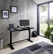 Moderner E-Schreibtisch in einem hellen Raum mit Blick auf den Garten, ausgestattet mit Monitor, Laptop und Schreibtischzubehör.