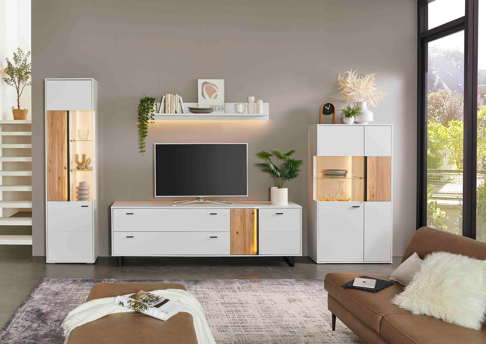 Moderne Wohnzimmermöbel mit LED-Beleuchtung, bestehend aus einem Highboard links, einem TV-Lowboard in der Mitte und einem Highboard rechts, in einer hellen, stilvollen Umgebung. Frontalansicht.