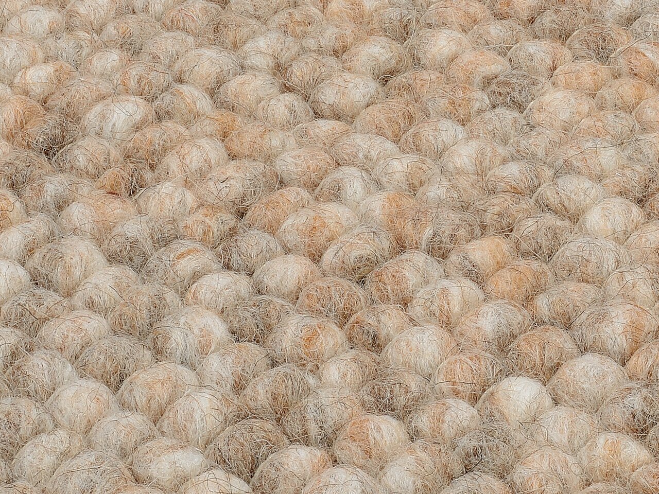 Nahaufnahme eines handgewebten Teppichs mit einer texturierten, kugelförmigen Oberfläche in natürlichen Beige- und Brauntönen.