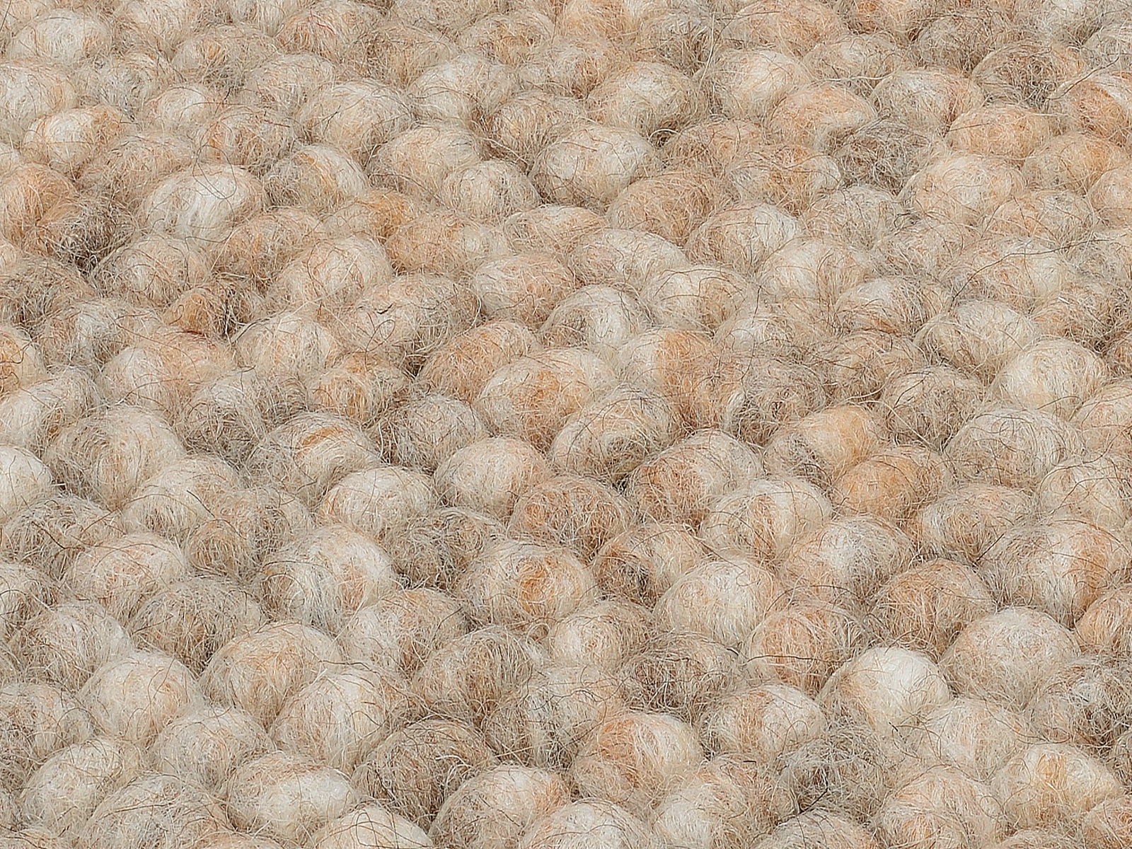 Nahaufnahme eines handgewebten Teppichs mit einer texturierten, kugelförmigen Oberfläche in natürlichen Beige- und Brauntönen.