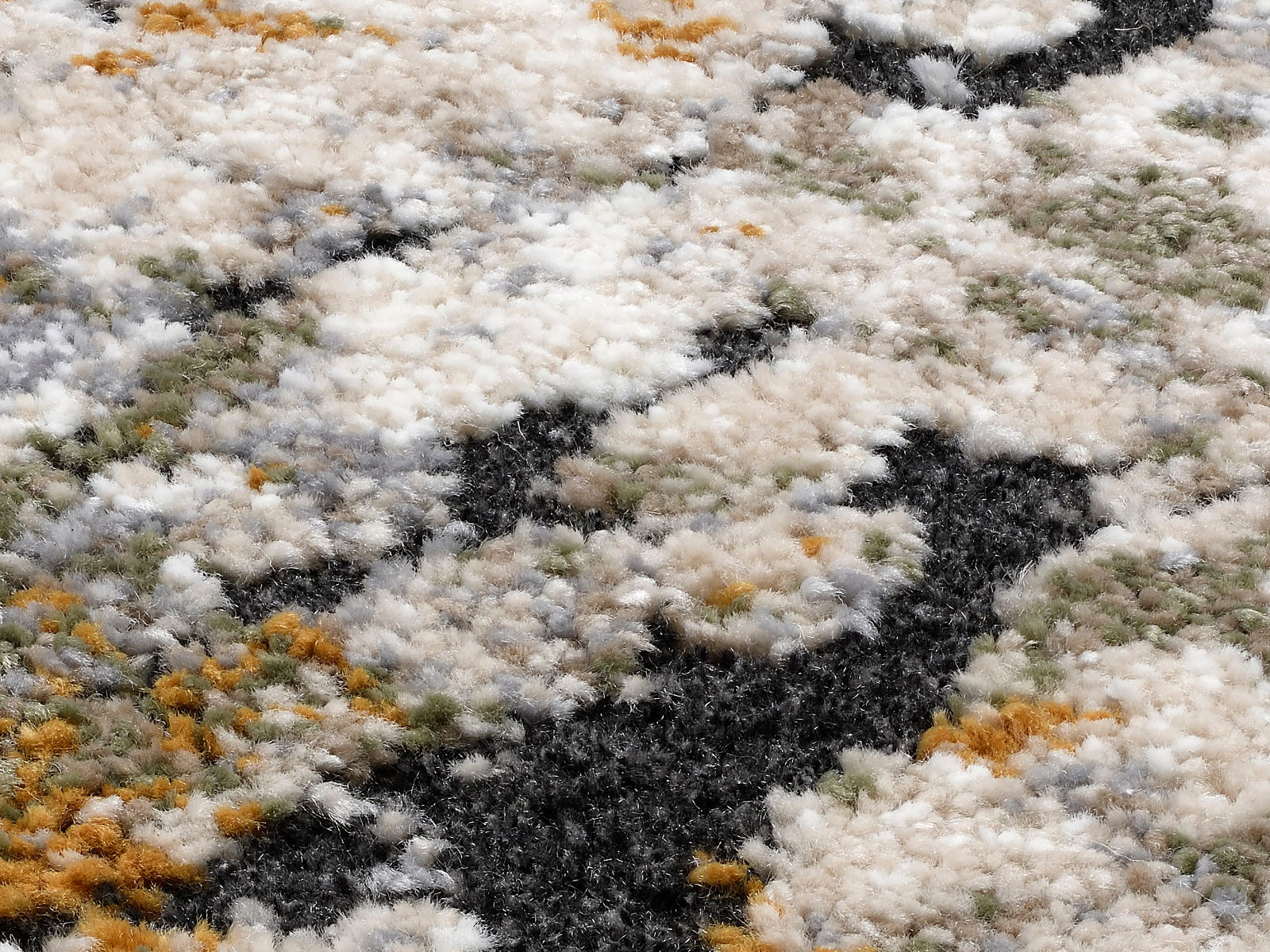Nahaufnahme eines Designer-Teppichs mit flauschiger Textur und einem Muster in Weiß, Schwarz, Grün und Orange, aus seitlicher Perspektive aufgenommen.