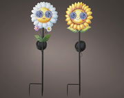 Zwei Solar Stabbeleuchten in Form von fröhlichen Blumen mit Sonnenbrillen, eine mit weißen Blütenblättern und eine mit gelben, auf einem dunklen Hintergrund. Vorderansicht.