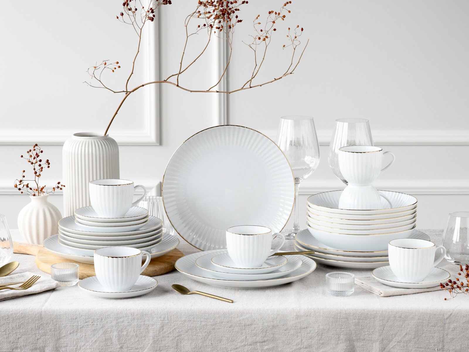 creaTable Kombiservice 30-tlg ALLEGRA Elegantes weißes Porzellan-Tafelservice mit feiner Rillenstruktur und Goldrand, arrangiert mit Tellern, Tassen und Schalen auf gedecktem Tisch; frontale Perspektive auf das Set.