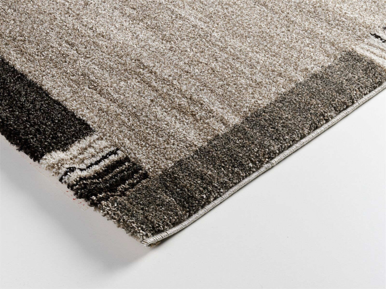 Nahaufnahme einer Ecke des Teppichs Castle Flora, ca. 140x200cm, mit einem modernen, mehrfarbigen Design in Erdtönen. Perspektive von oben.