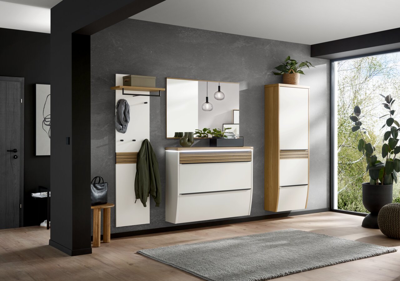 Moderne Garderobeneinrichtung mit Spiegel, Hängeschuhschrank und Garderobenpaneel in einem hellen Raum mit Blick auf eine grüne Außenlandschaft.