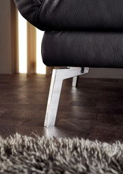 Nahaufnahme eines schwarzen Ledersofas mit verchromtem Metallfuß, seitliche Perspektive.