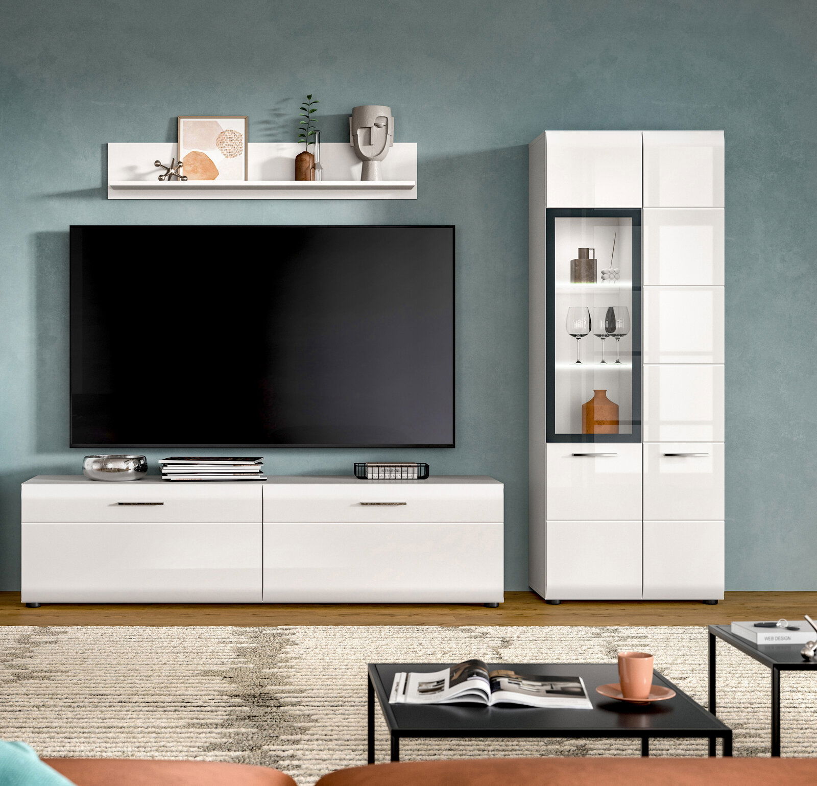 Modernes weißes TV-Lowboard mit großem Flachbildfernseher und passender Vitrine mit Glasfront im Wohnzimmer, frontal aus Augenhöhe fotografiert