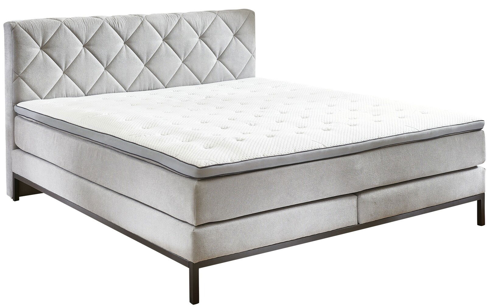 Boxspringbett in seitlicher Perspektive mit gestepptem Kopfteil und eleganten Metallfüßen