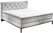 Boxspringbett in seitlicher Perspektive mit gestepptem Kopfteil und eleganten Metallfüßen