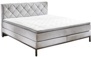 Boxspringbett in seitlicher Perspektive mit gestepptem Kopfteil und eleganten Metallfüßen