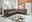 Große, moderne Polsterrundecke in einem hellen Wohnzimmer mit großen Fenstern, die viel Tageslicht hereinlassen. Die Couch ist in einem warmen Braunton gehalten und bietet viel Platz zum Entspannen. Perspektive von vorne links.
