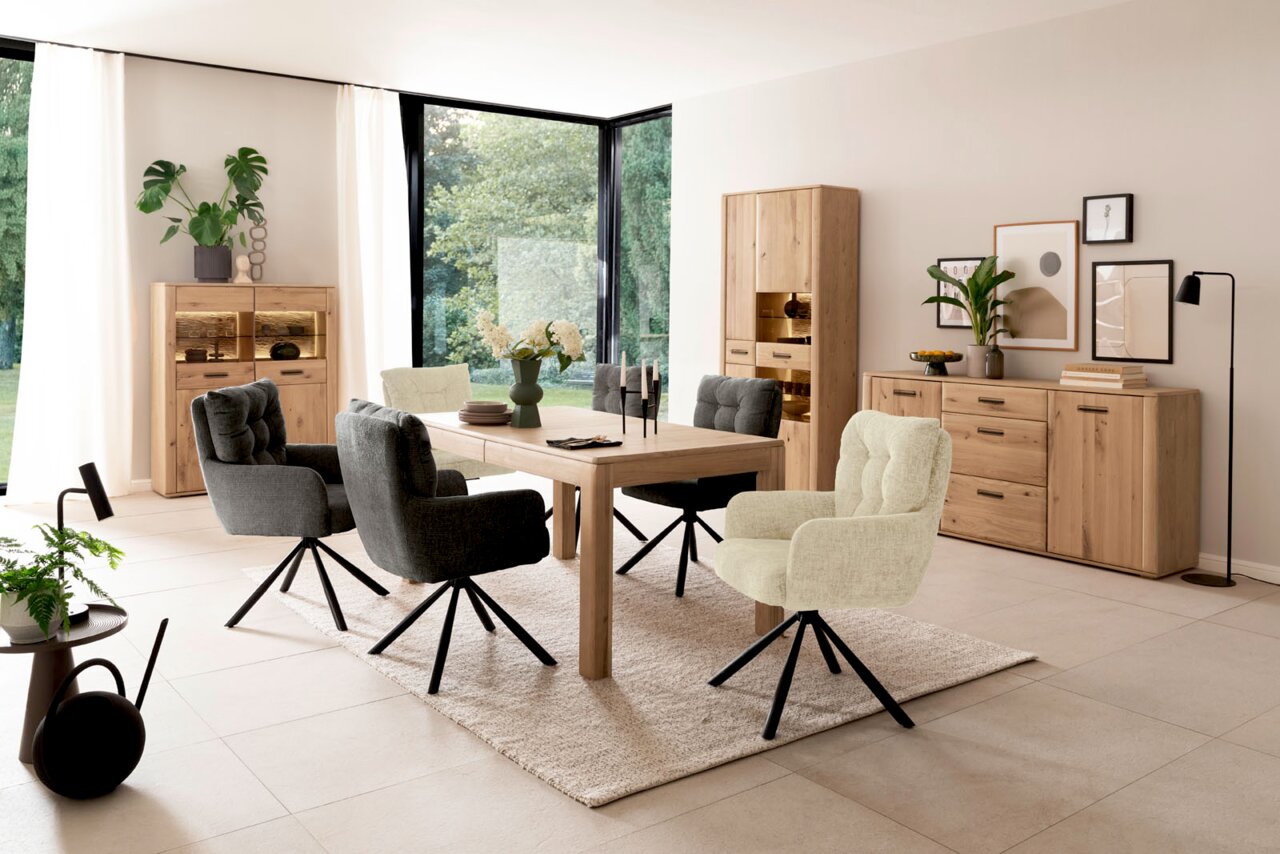 Modernes Esszimmer-Set mit rechteckigem Holzesstisch, vier gepolsterten Drehstühlen in Grau und Hellgrün sowie passenden Holz-Sideboards und Vitrine; Perspektive: frontale Weitwinkelansicht auf die Essgruppe im Raum.