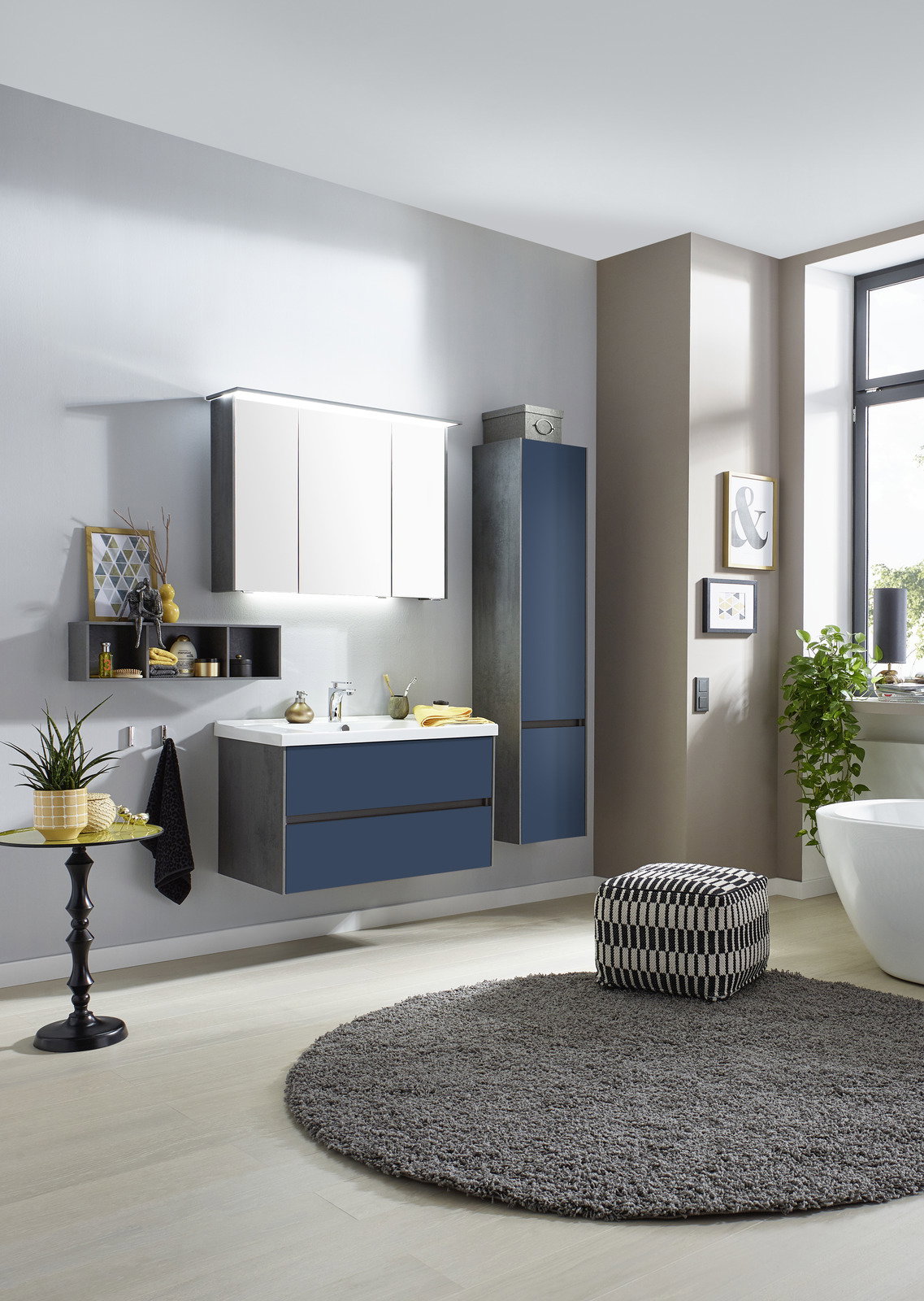 Dieter Knoll Badkombination 3-tlg. LORETO Moderne Badkombination in einer stilvollen Badezimmerumgebung, bestehend aus einem Waschtisch mit blauen Schubladen, einem Hängeschrank und einem Spiegelschrank, seitliche Perspektive.