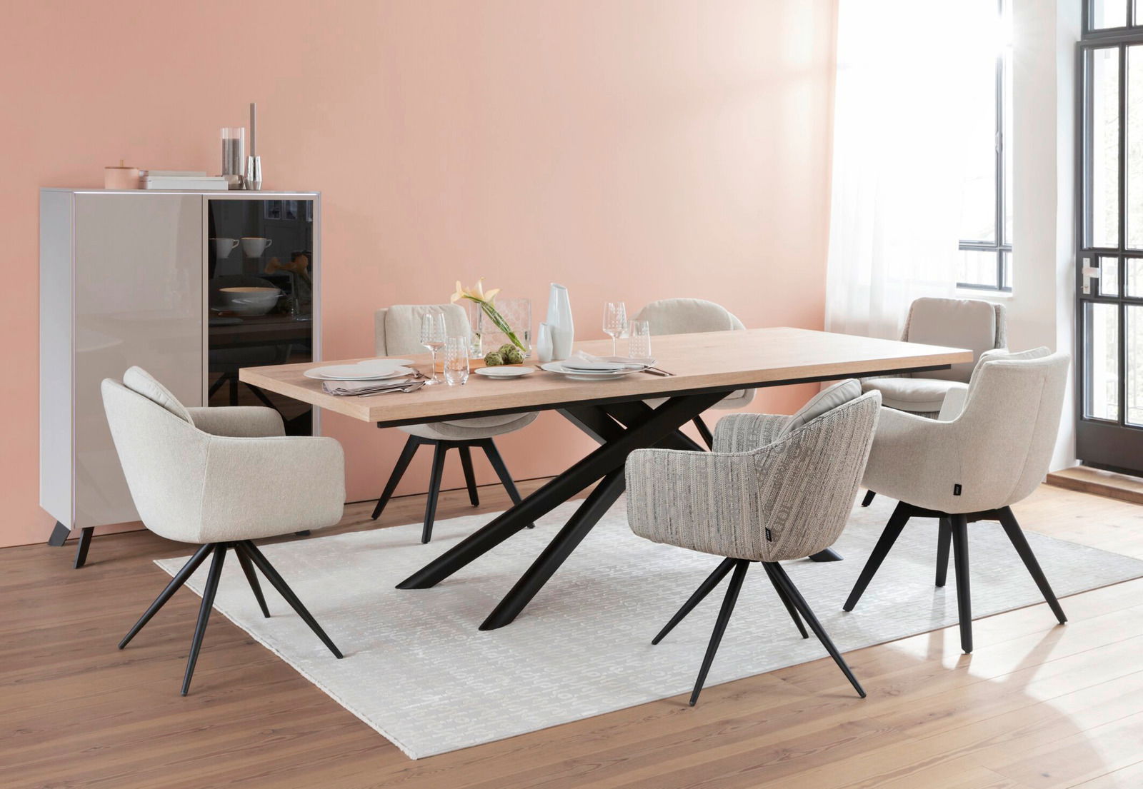 Moderner Esstisch mit hellem Holz und schwarzen Metallbeinen, umgeben von gepolsterten Stühlen in einem eleganten Esszimmer mit Blick auf die Tischplatte.