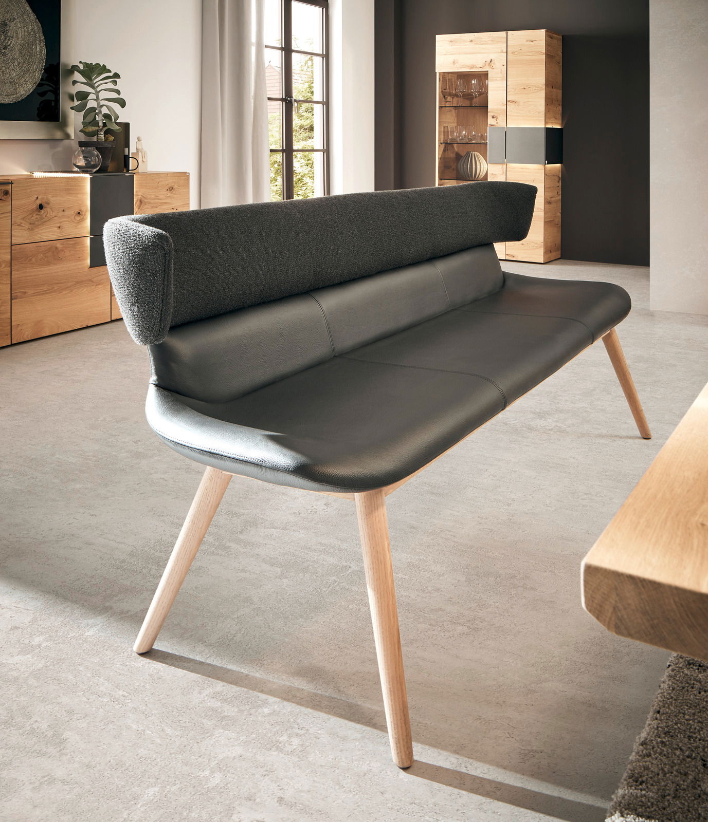 Moderne Bank mit schwarzem Lederbezug und Holzbeinen, seitliche Perspektive im Wohnzimmer.