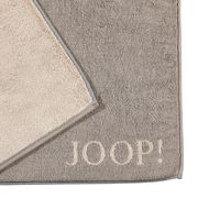Graue Badematte mit beigem Rand und dem Schriftzug 'JOOP!' in der Ecke, von oben fotografiert.