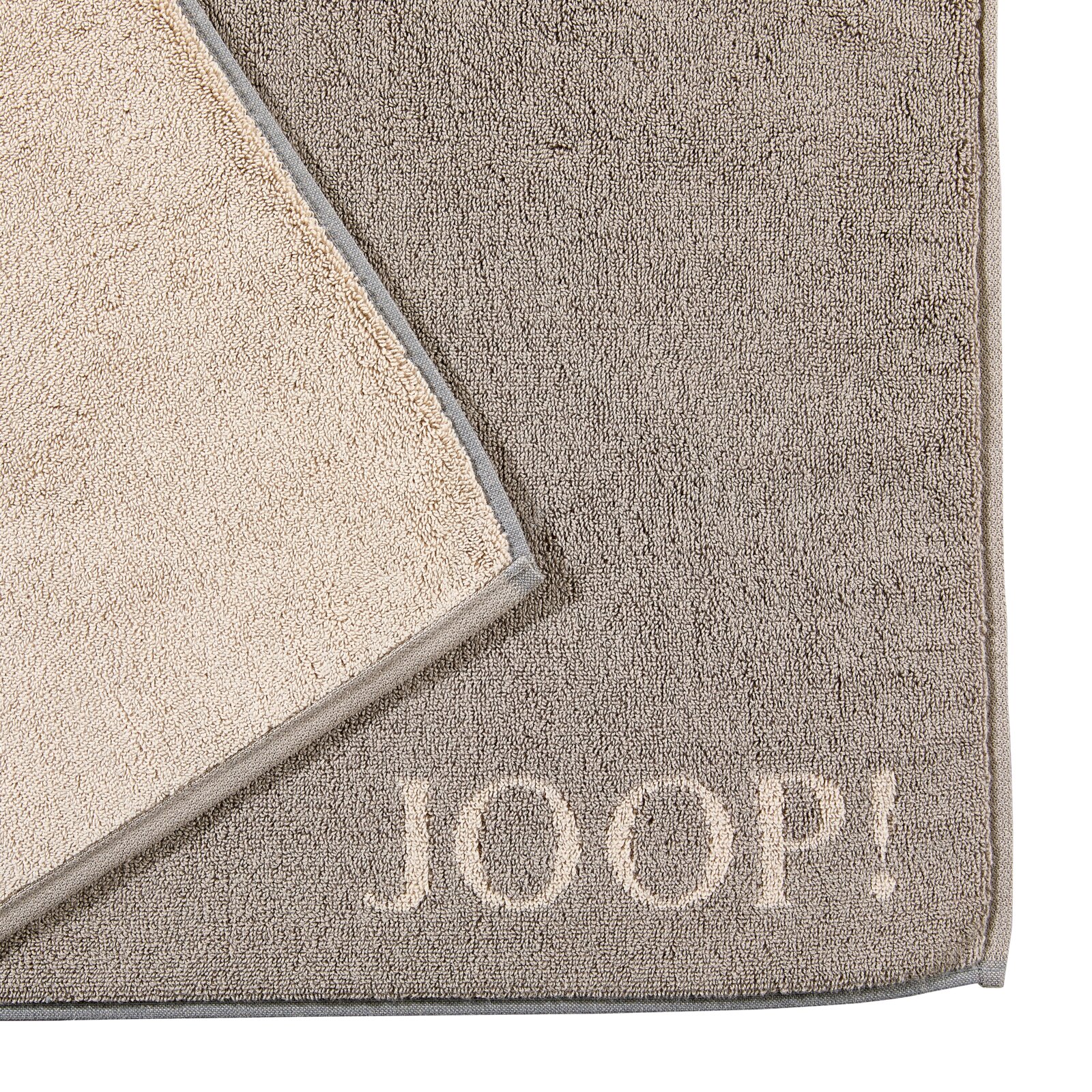 Grijze badmat met een beige rand en het opschrift 'JOOP!' in de hoek, gefotografeerd van bovenaf.