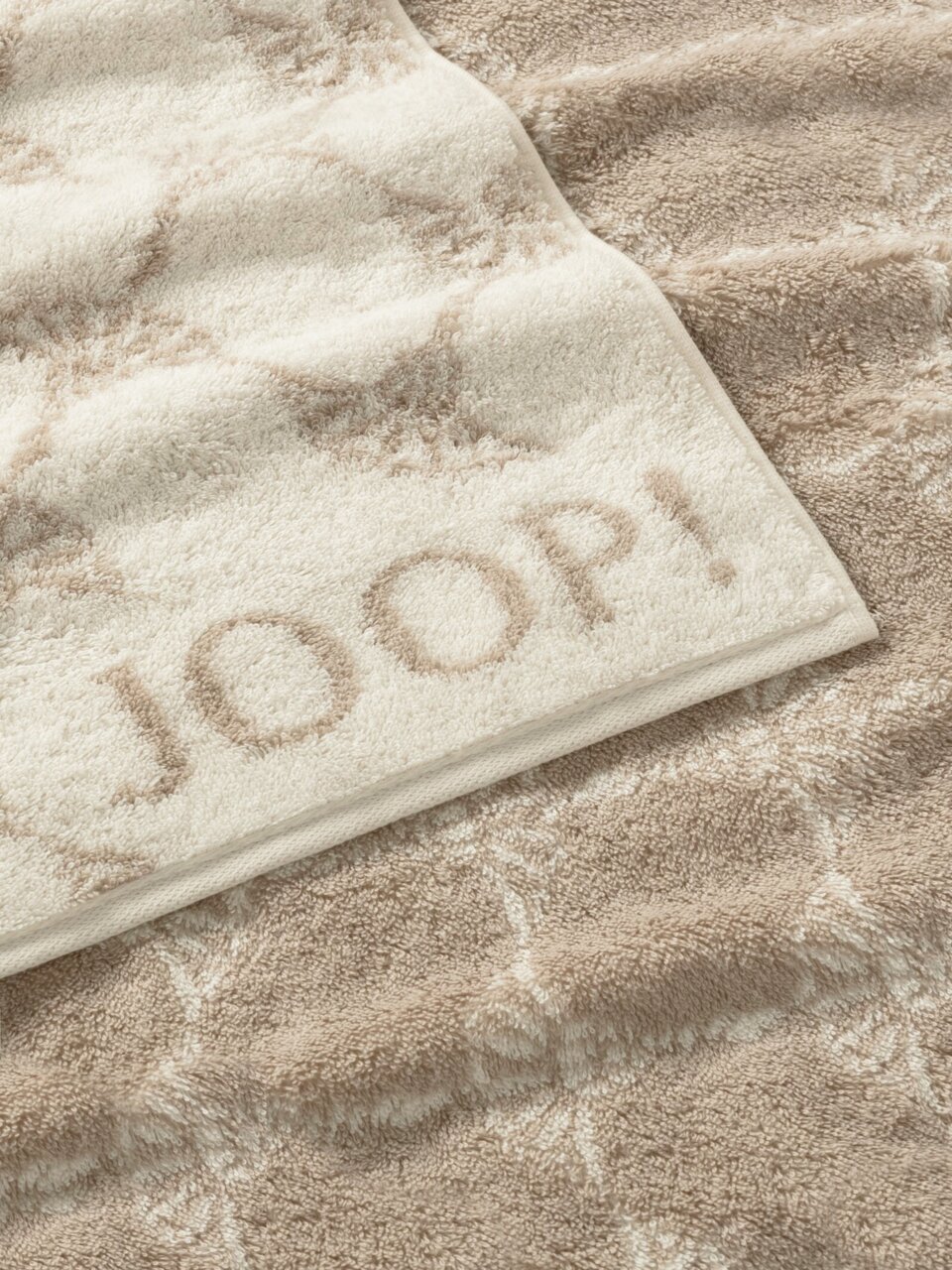 Beiges Gästetuch mit eingewebtem Muster und dem Schriftzug 'JOOP!' in Nahaufnahme.