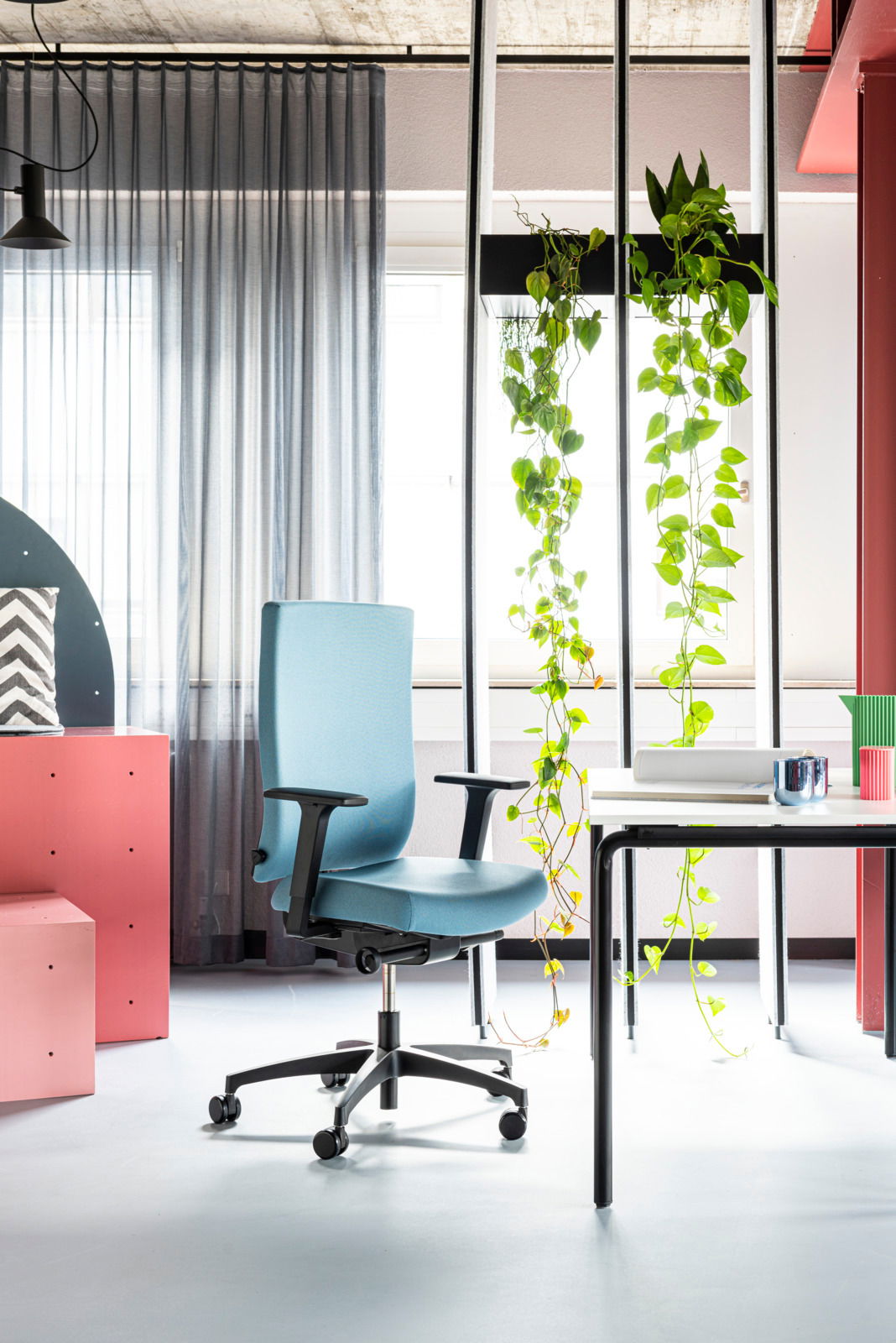 Moderner blauer Drehstuhl mit Armlehnen in einem stilvoll eingerichteten Büro, seitliche Perspektive.