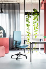 Moderner blauer Drehstuhl mit Armlehnen in einem stilvoll eingerichteten Büro, seitliche Perspektive.