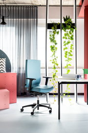 Moderner blauer Drehstuhl mit Armlehnen in einem stilvoll eingerichteten Büro, seitliche Perspektive.