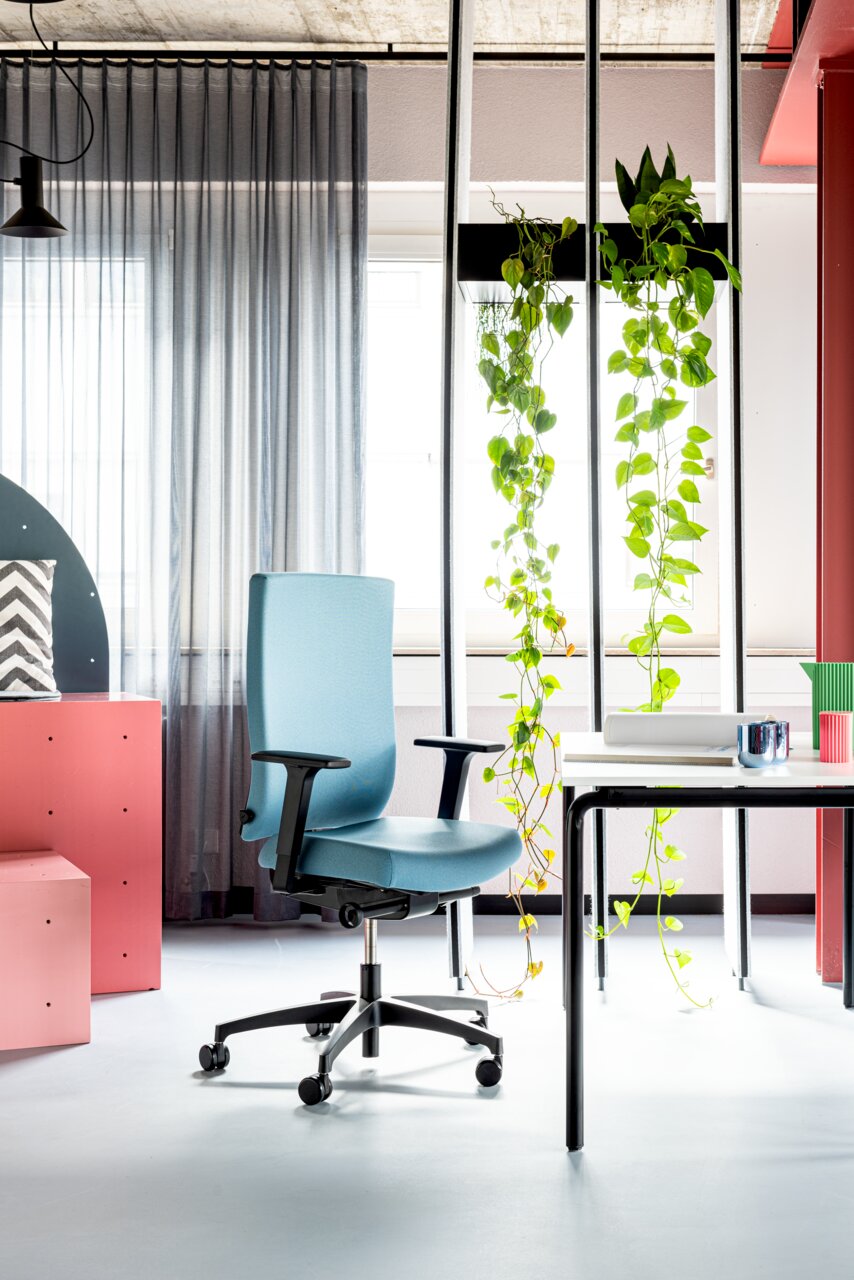 Moderner blauer Drehstuhl mit Armlehnen in einem stilvoll eingerichteten Büro, seitliche Perspektive.